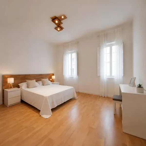 Dormitorio amplio con suelo de madera y dos ventanas