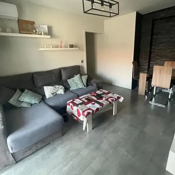 Salón con sofá chaise longue gris y zona de comedor
